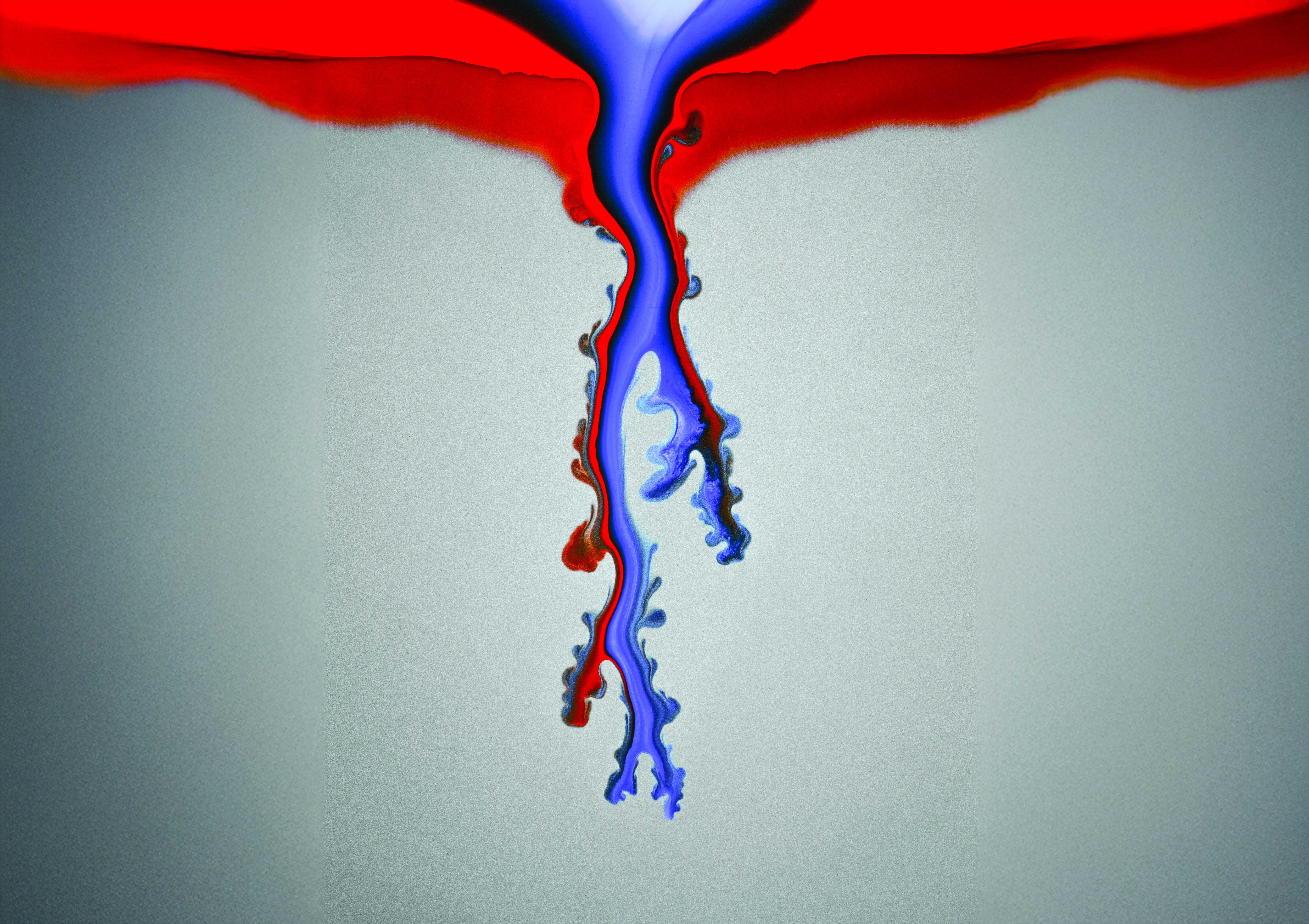 Water, dyed in red and blue, creates descending fingerlike patterns as it penetrates through a dense bed of sand grains.