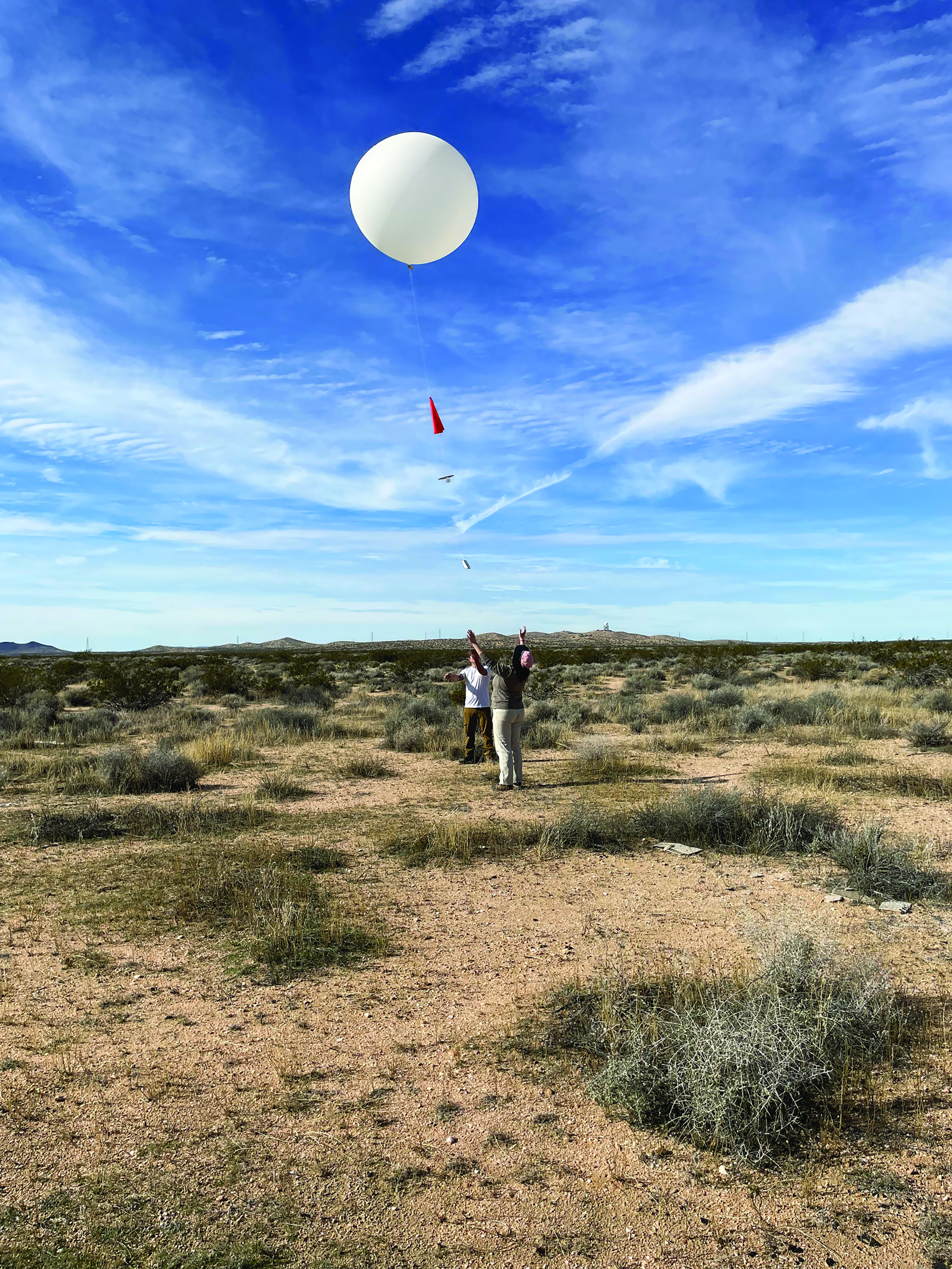 Two people in the desert launch a weather balloon.