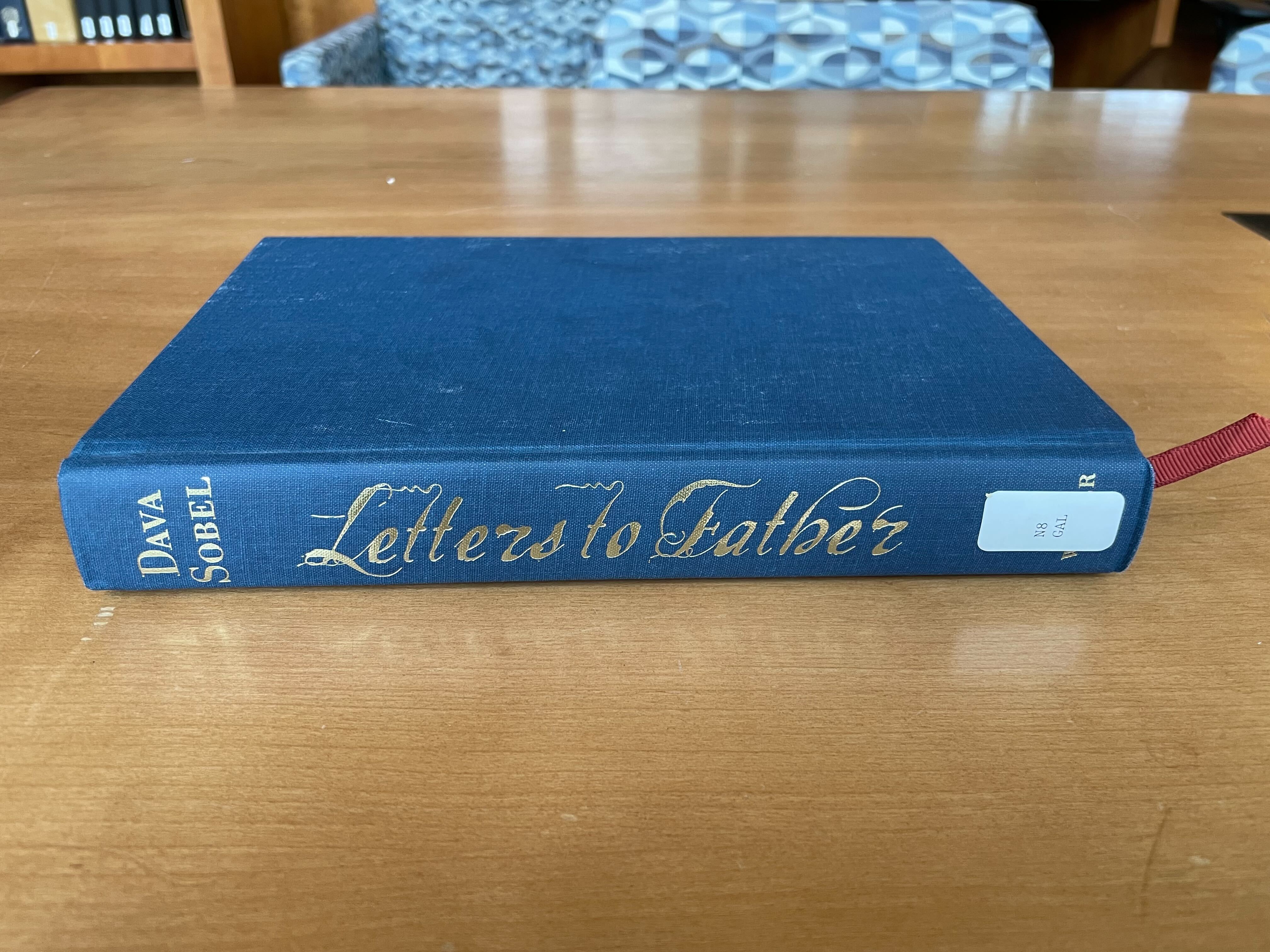 Book laying on its side on a table, "Dava Sobel: Letters to Father" on its spine.