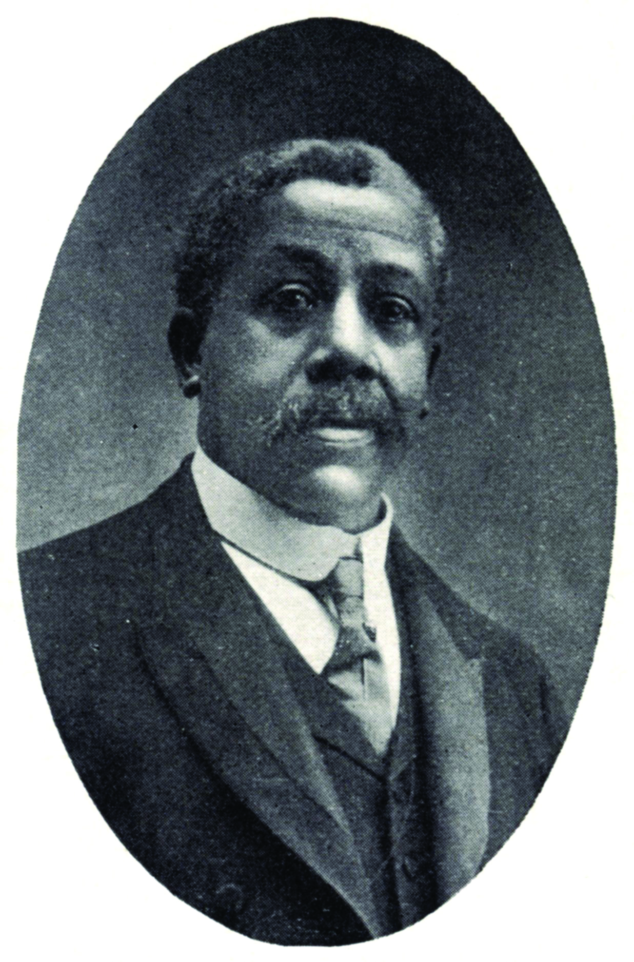 An older man with a salt-and-pepper mustache wearing a suit and tie.