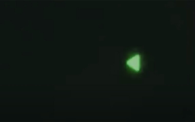 A glowing green triangle on a black background