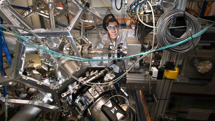 A man Raul Acevedo stands behind a large elaborate machine