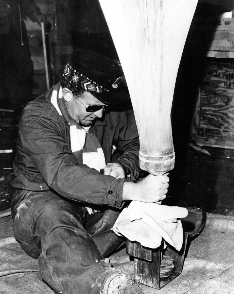 Man seated wearing sunglasses with his hand on the bottom of a balloon