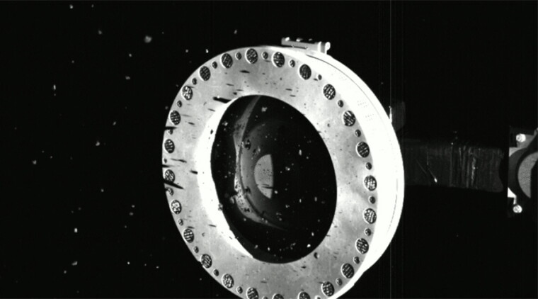 An image of asteroid material escaping from the sample collection system of NASA’s OSIRIS-REx spacecraft.