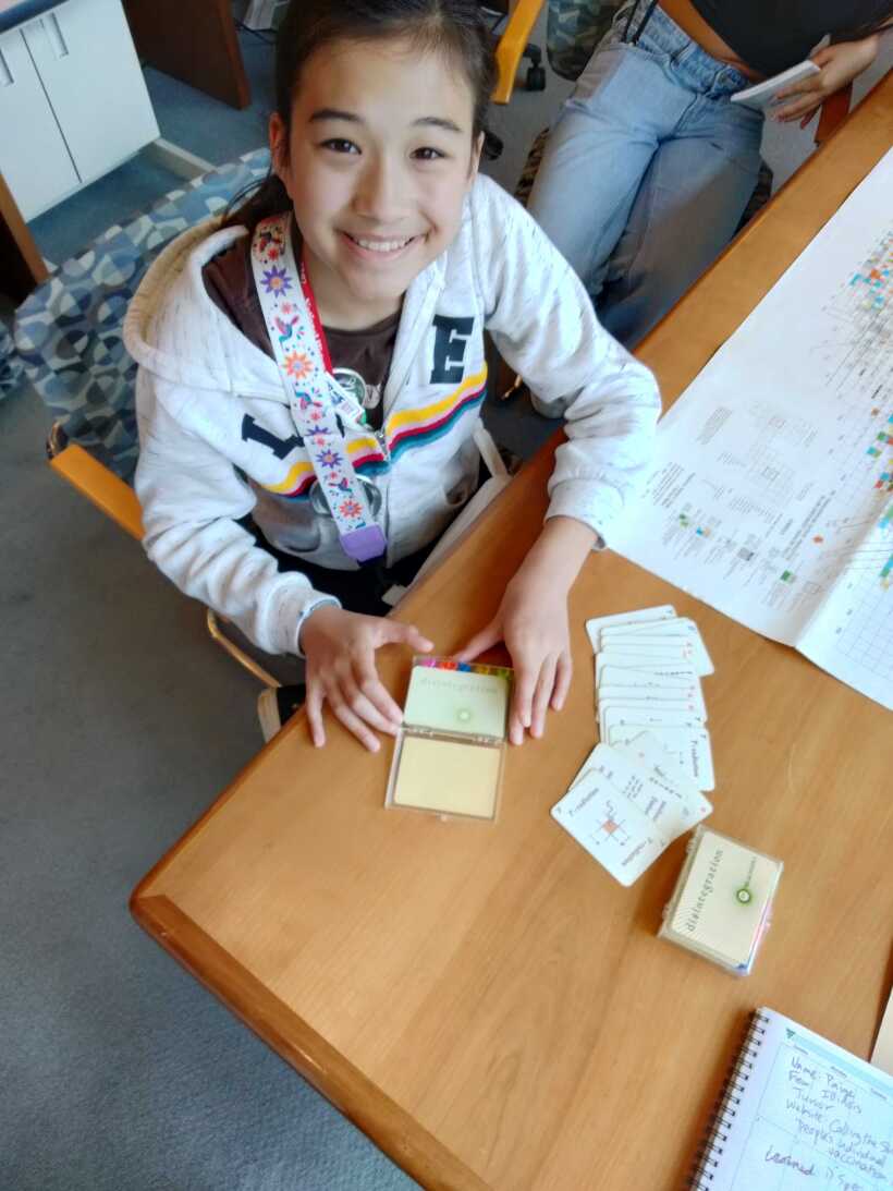 Girl looking up from a desk with papers on it.