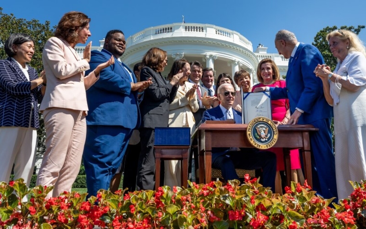 President Biden signs the CHIPS and Science Act outside the White House while many lawmakers look on