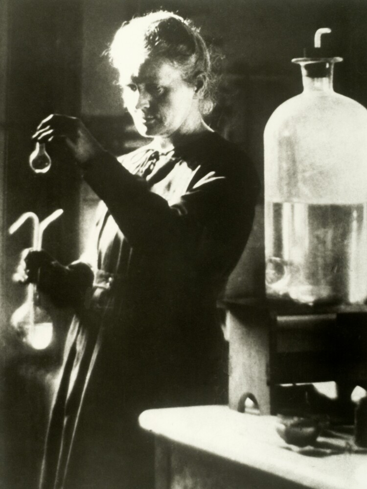 Marie Curie holds a up a vial in a lab.