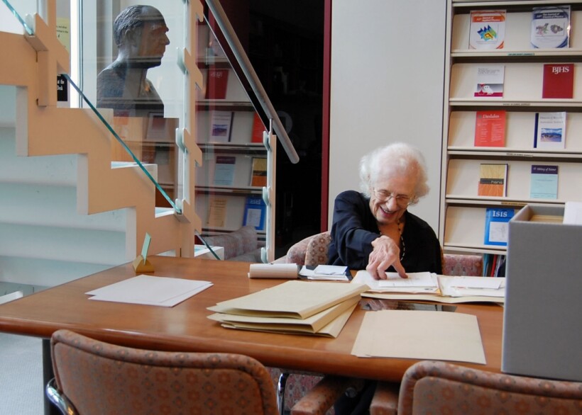 Nancy Roman sitting at desk looking at Archival papers