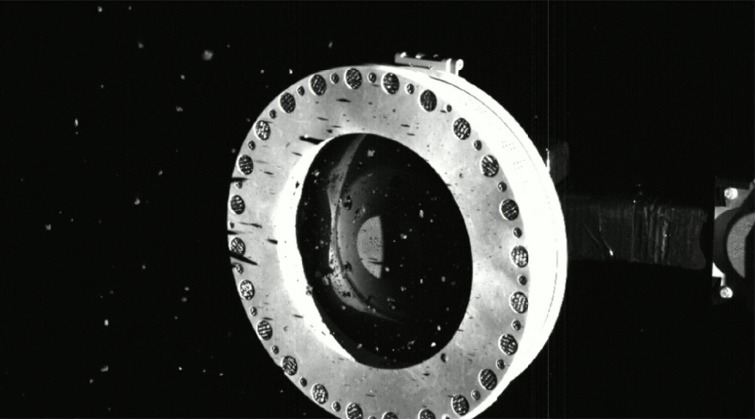An image of asteroid material escaping from the sample collection system of NASA’s OSIRIS-REx spacecraft.