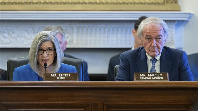 A woman and a man sitting behind a wooden desk.