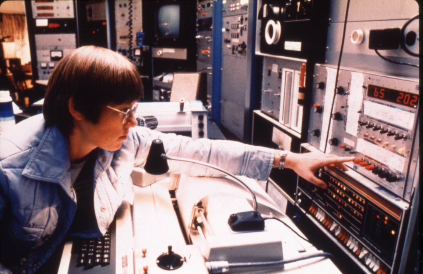 Faber reaching over a control board to adjust a dial on telescope controls.