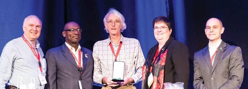 Neuenschwander (Center) with (L to R) AIP CEO Robert G.W. Brown, Sigma Pi Sigma President Willie S. Rockward, Society of Physics Students President DJ Wagner, and SPS & Sigma Pi Sigma Director Brad R. Conrad.