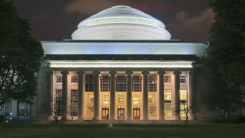 A white domed building lit up against a black sky.