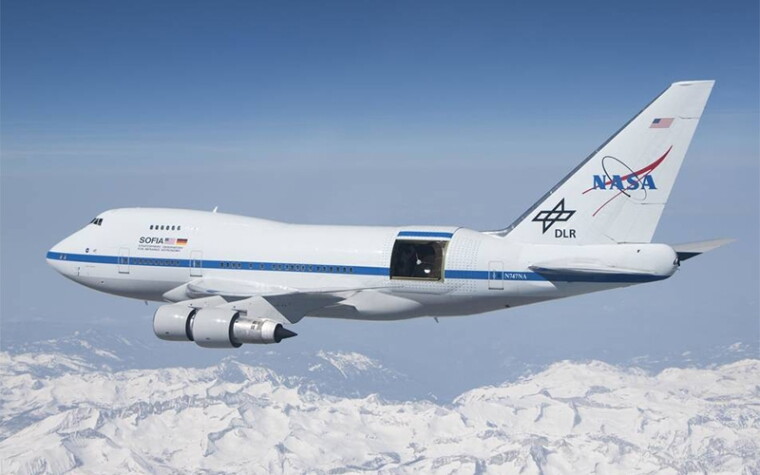 An airplane hosting the SOFIA instrument flying above mountains