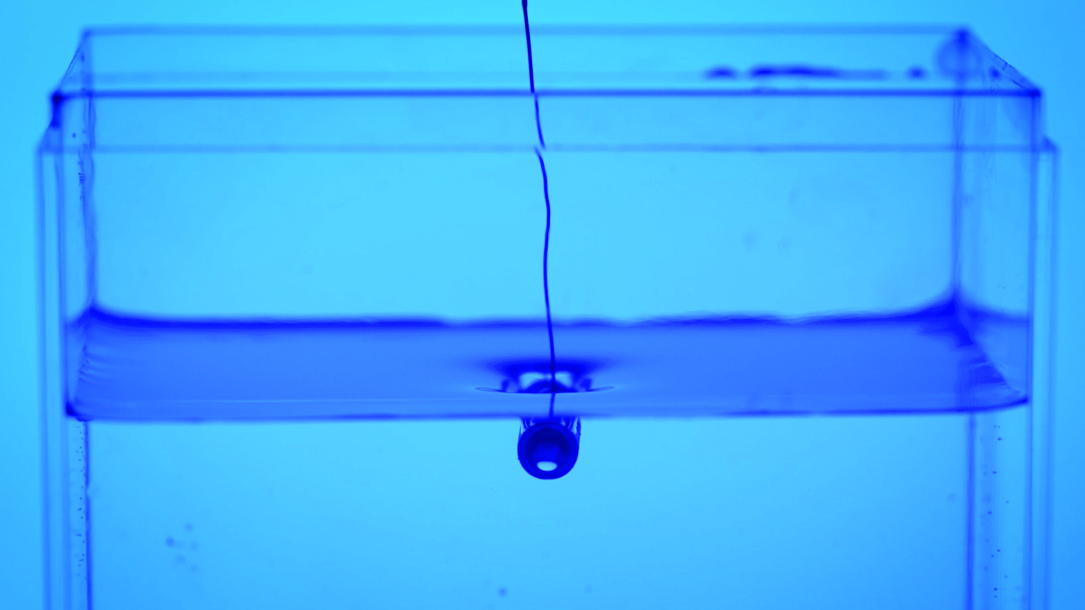 A dimple is formed in the water around a submerged tube.